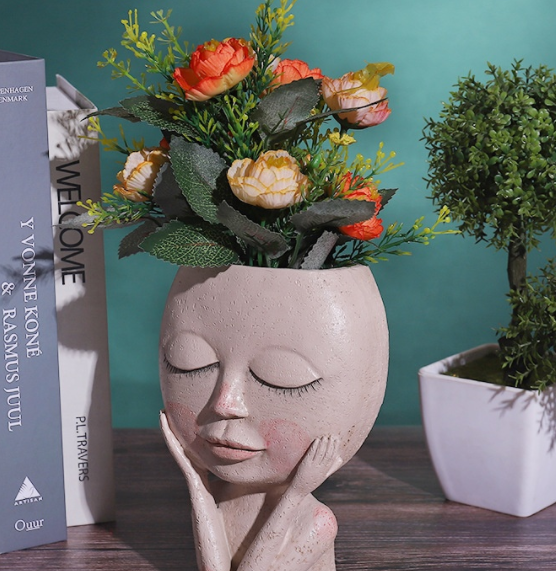 female face planter with artificial flowers